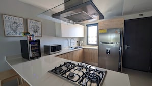 Een moderne keuken met een gasfornuis, roestvrijstalen apparatuur en houten keukenkastjes.