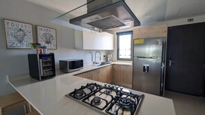 Eine moderne Küche mit Gasherd, Edelstahlgeräten und Holzschränken.
