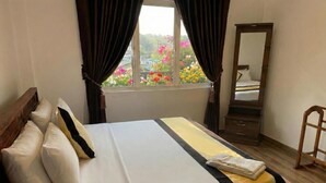 A neatly made bed with a white and black bedspread, a wooden headboard, and a window with curtains. - Full Moon Hotel (Nuwara Eliya)