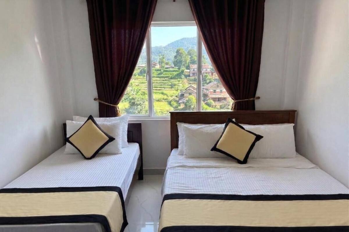 Deux lits simples avec des têtes de lit, une fenêtre avec des rideaux et une vue sur un paysage verdoyant.