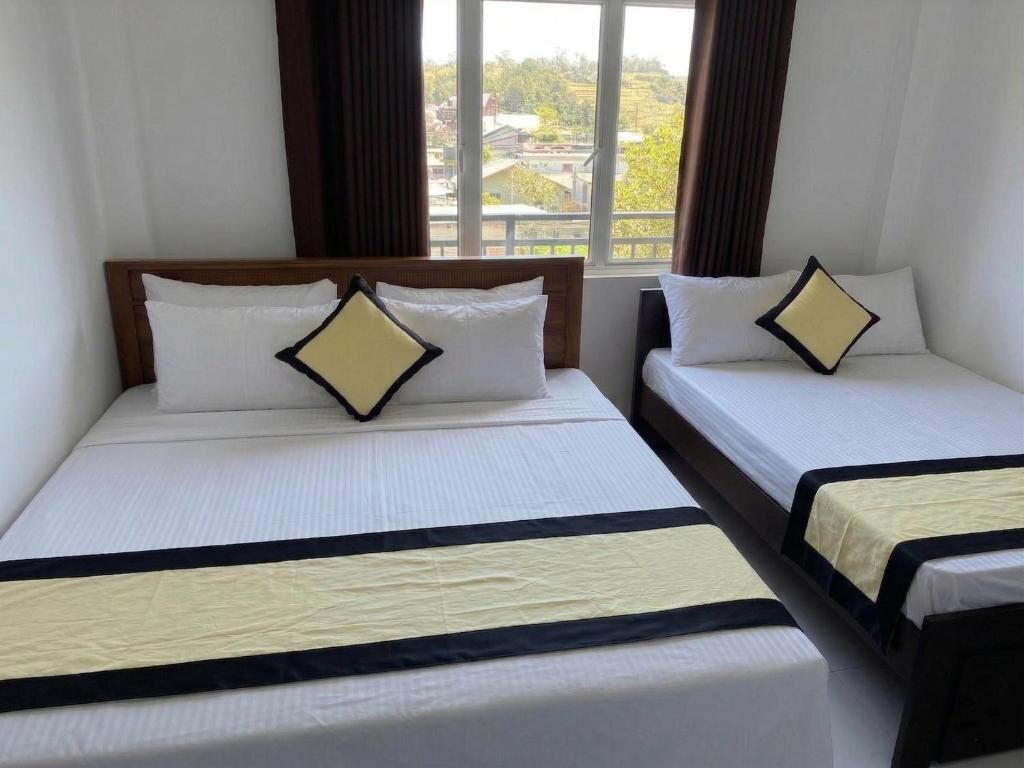 Two single beds with headboards, white bedding, and a window with curtains.