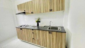 A kitchen with wooden cabinets, a gas stove, a sink, and a small potted plant. - Full Moon Hotel (Nuwara Eliya)