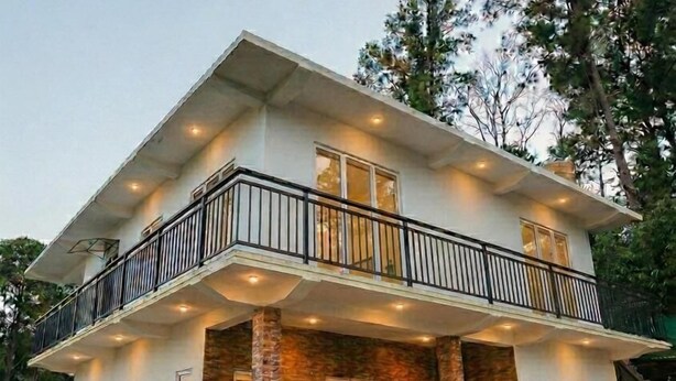 A two-story house with a balcony, stone columns, and a flower garden. - Full Moon Hotel (Nuwara Eliya)