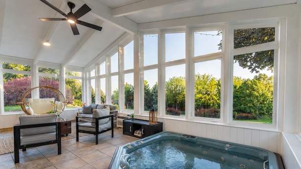 A sunlit room with a hot tub, large windows, a ceiling fan, and a seating area with a table and chairs. - Mountain Luxury Retreat (Orem)