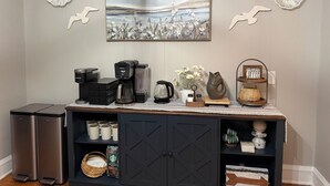 A kitchenette with a coffee maker, a kettle, and a coffee station.