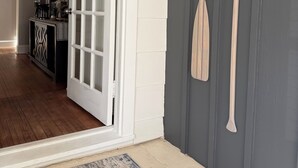 A doorway leading to a room with a wooden floor, a coffee station, and a wall with two wooden paddles.