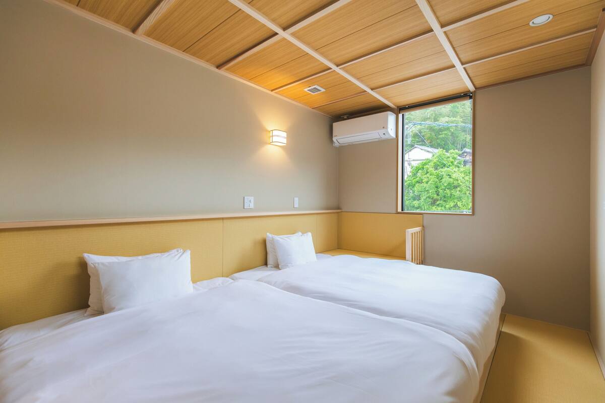 Ein Hotelzimmer mit Holzboden, einem großen Fenster mit Ausblick und einem Bett mit weißer Bettwäsche.