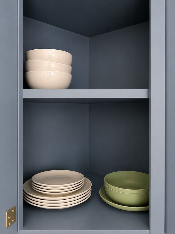 A kitchen cabinet with two shelves, each holding bowls and plates.