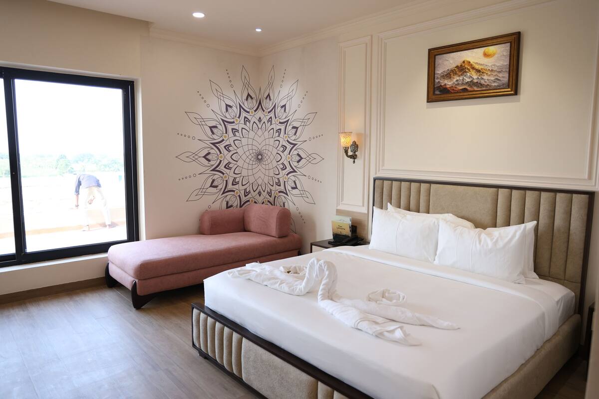 Una habitación de hotel con una cama, un sofá rosa, un mural en la pared y un cuadro.
