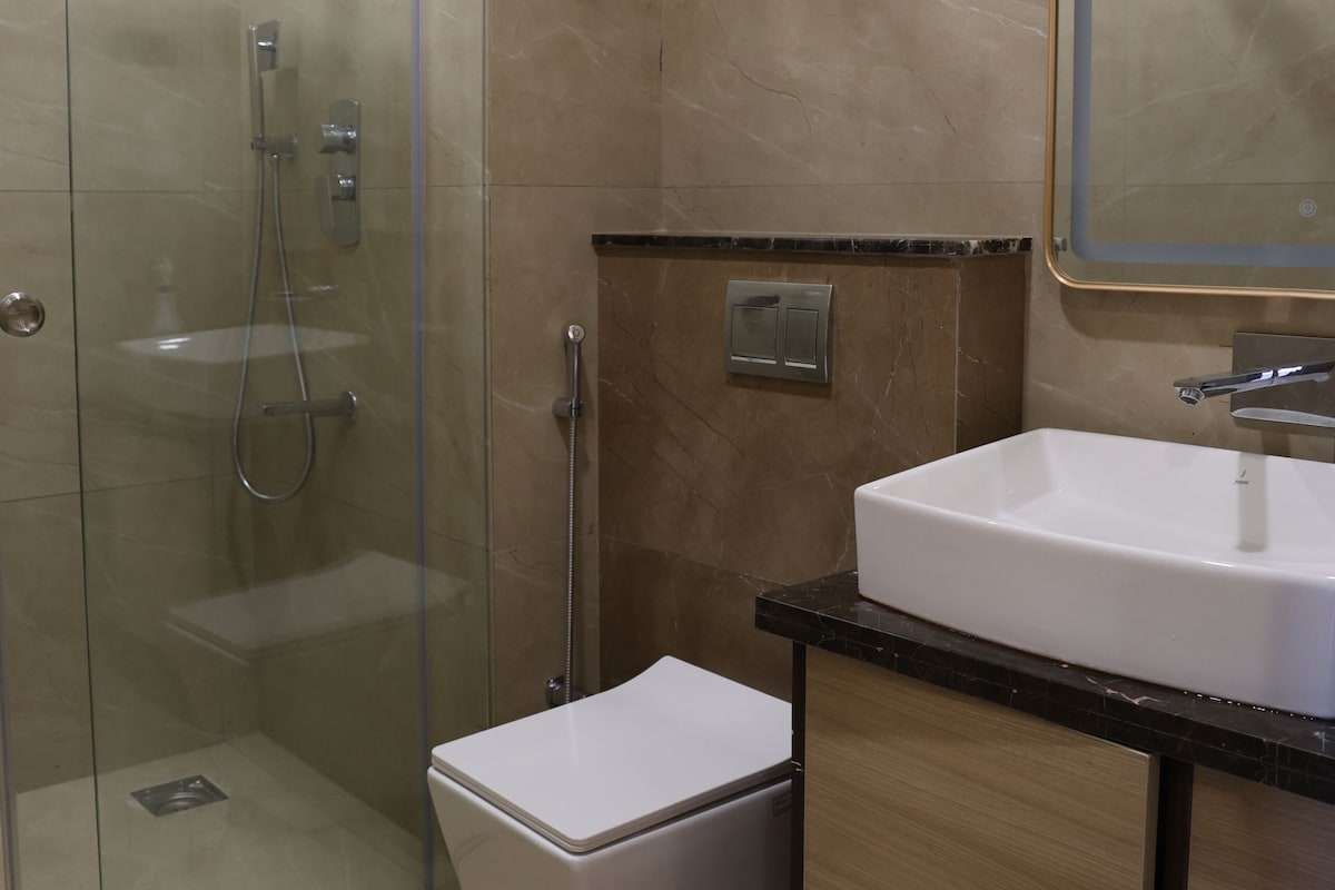 Une salle de bain avec une douche à parois de verre, un lavabo blanc et un miroir au-dessus.