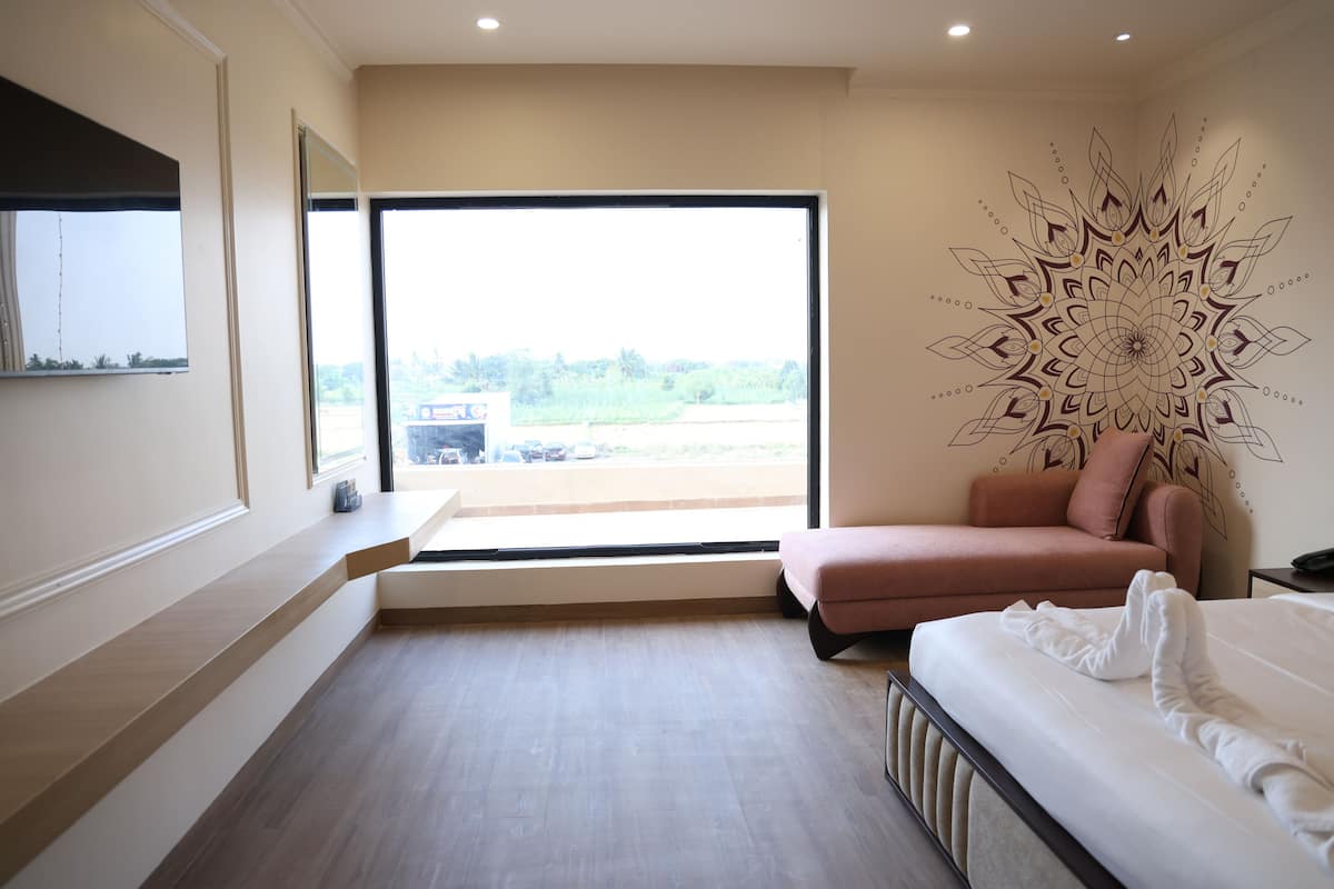 Un dormitorio con un ventanal grande, un sofá rosa, una cama y un mural en la pared.