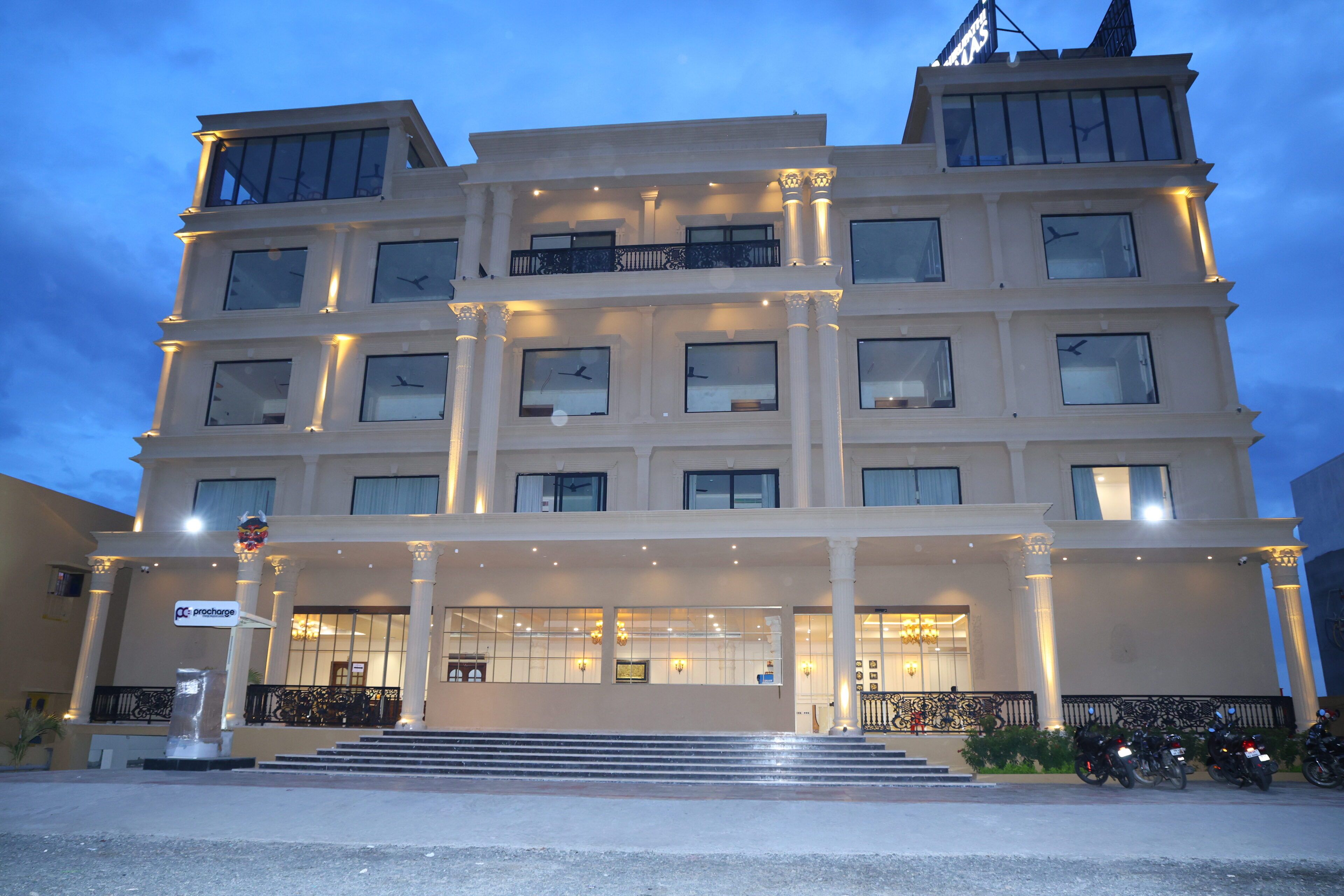 A multi-story hotel with a grand entrance, multiple balconies, and a well-lit facade.