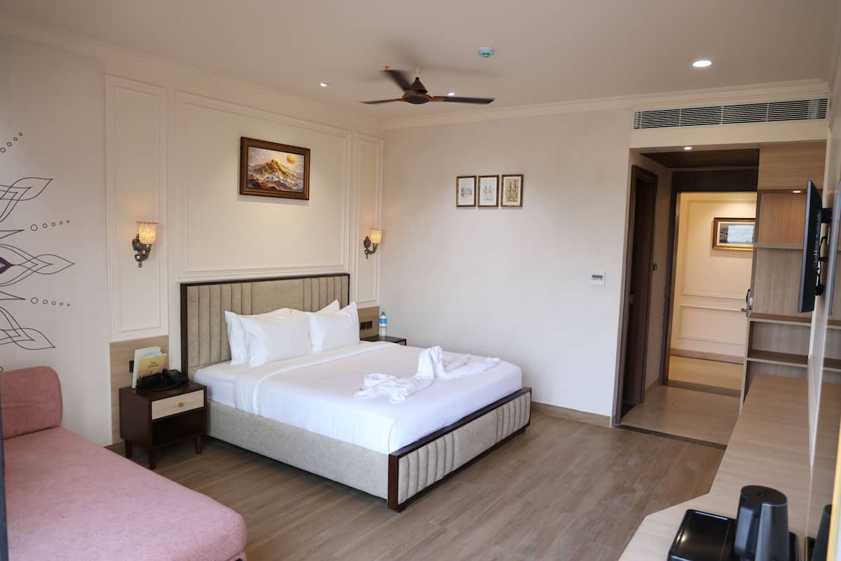 Habitación de hotel con cama, mesitas de noche, ventilador de techo y puerta que da a un baño.