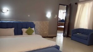 Een slaapkamer met een bed, een blauwe bank en een gang die naar een trap leidt.