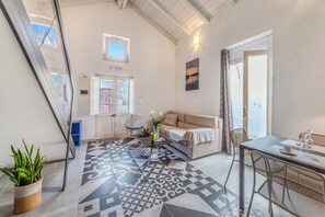 A modern living room with a patterned floor, a sofa, a dining table, and a potted plant. - Martano Jacuzzi Suite w/ Terrace & BBQ (Martano)