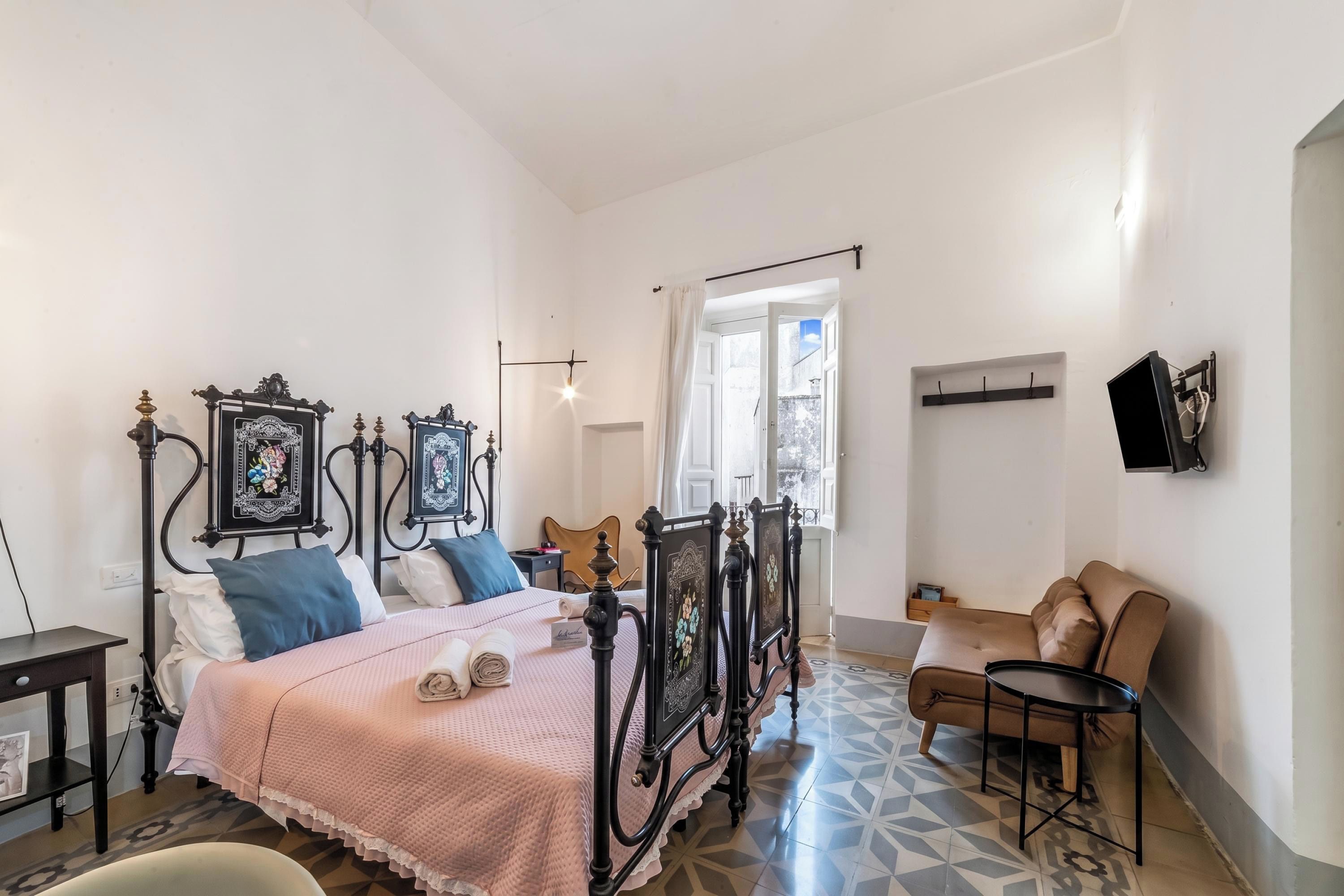 Quarto com cama, cadeira, mesa e televisão.