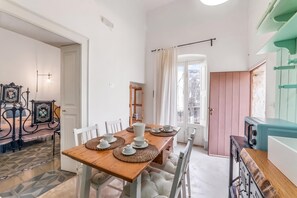 A dining area with a wooden table set for four, surrounded by white chairs. - Casa Tafuri In The Historic Center (Soleto)