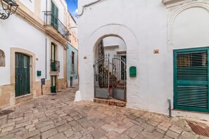 A narrow cobblestone street with buildings on either side, featuring arched doorways and numbered windows. - Casa Tafuri In The Historic Center (Soleto)