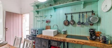 Una cocina con encimera de madera, un lavabo, un microondas y varios utensilios colgados en la pared.