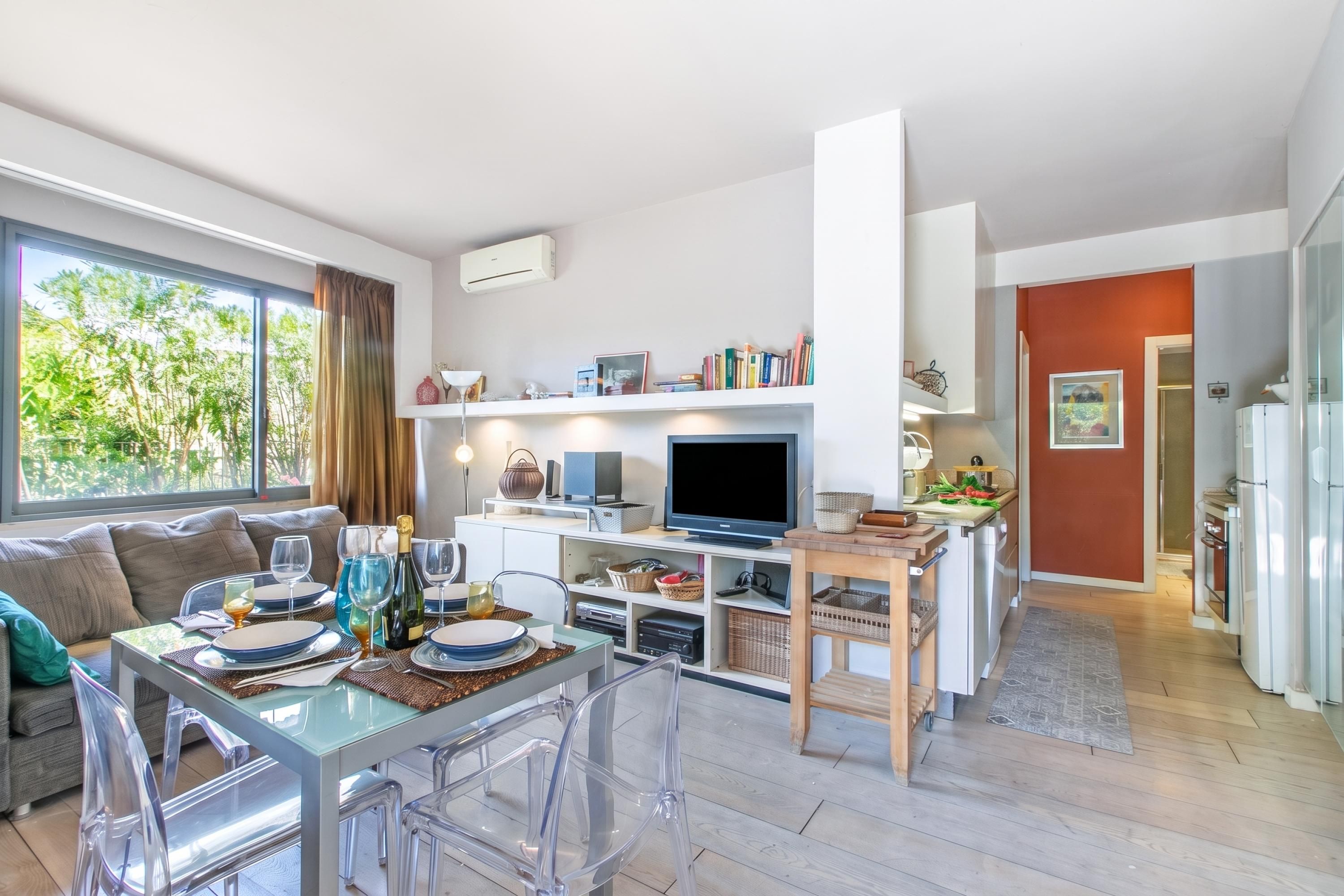A modern kitchen with a dining area, a TV, and a built-in bookshelf.