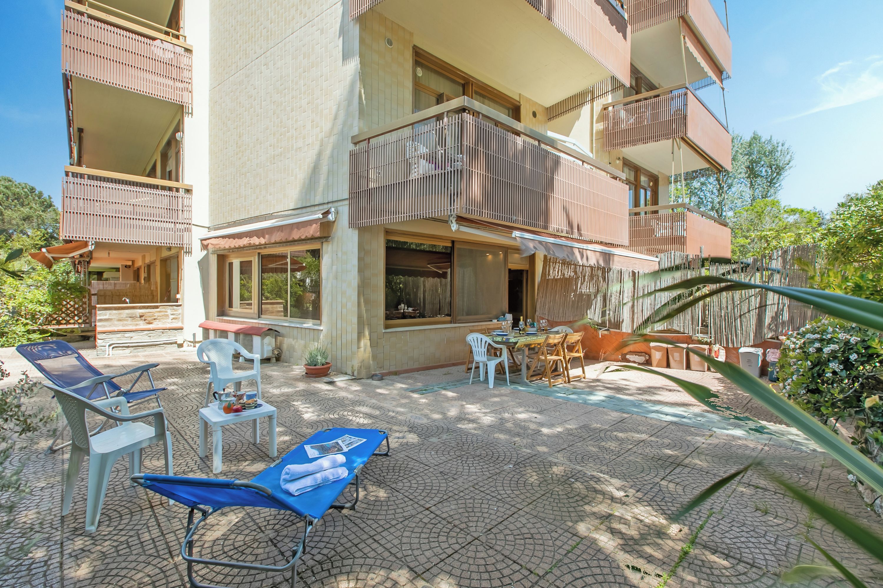 Un immeuble à plusieurs étages doté de balcons, d’un espace extérieur aménagé pour s’asseoir et d’une terrasse carrelée.