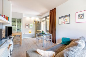 A modern living room with a flat-screen TV, a dining table with chairs, and a sofa. - Casa Piero With Private Garden and Parking (Viareggio)