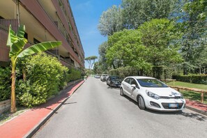 A street with parked cars, a red bike lane, and a building with balconies. - Casa Piero With Private Garden and Parking (Viareggio)