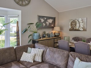 Ein Wohnzimmer mit braunem Sofa, einem Esstisch mit Stühlen, einer Lampe, einer Weltkarte und einem Buddha-Gemälde.