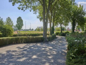A gravel pathway surrounded by neatly trimmed hedges and trees.
