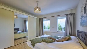 Une chambre à coucher avec un grand lit, une armoire, une fenêtre avec des rideaux et un luminaire au plafond.
