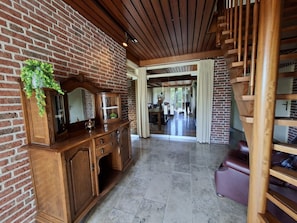 A spacious living area with a brick wall, wooden staircase, and a dining area. - Authentic holiday home at the cheese farm (Genderen)
