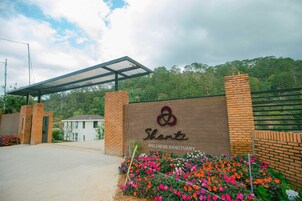 Entrada de um santuário de bem-estar, com muro de tijolos, galeria coberta e placa.