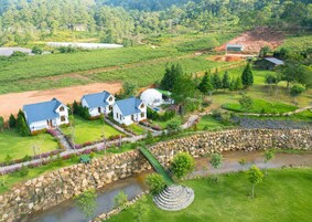 Área residencial com casas, uma ponte de pedra e um rio.