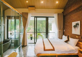 Quarto com cama grande, box de vidro e varanda com vista.