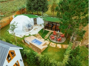 Una estructura de cúpula geodésica, una terraza de madera y un área de estar circular con un hogar.