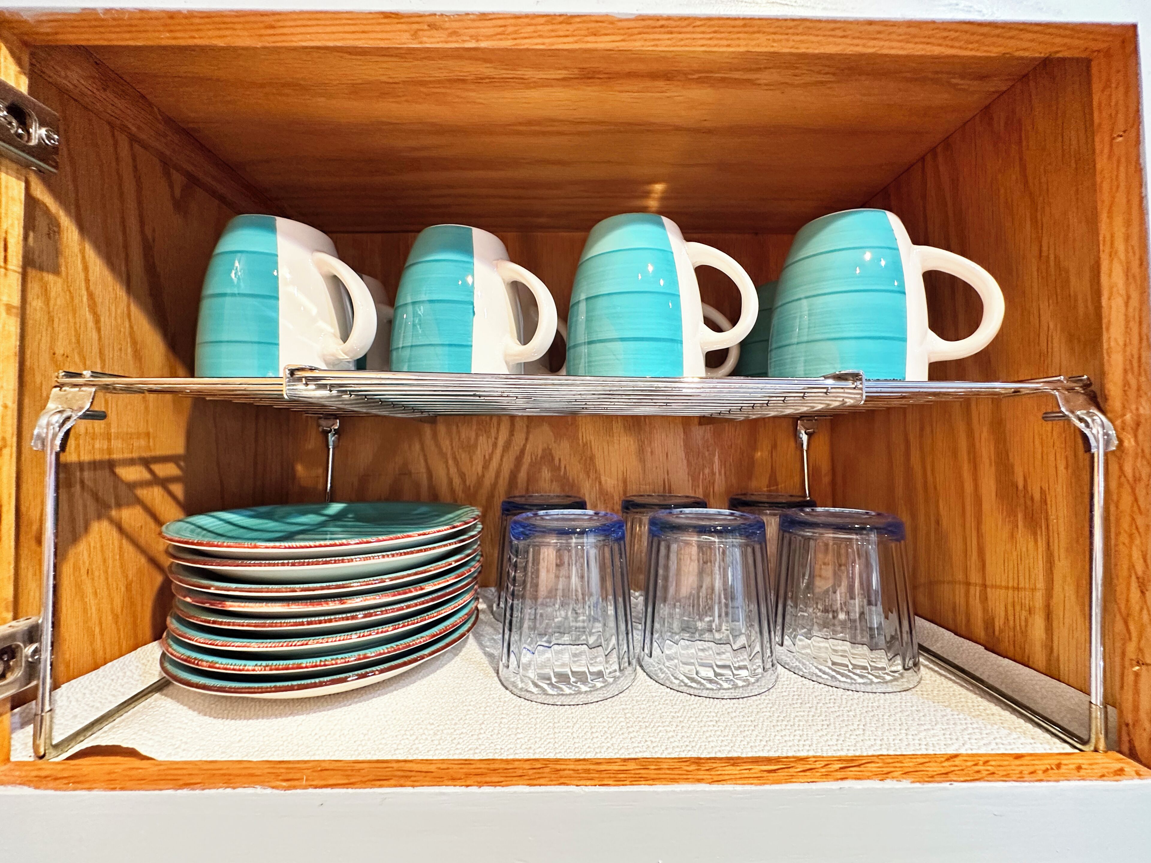 A storage cabinet with shelves holding plates, mugs, and glass jars.