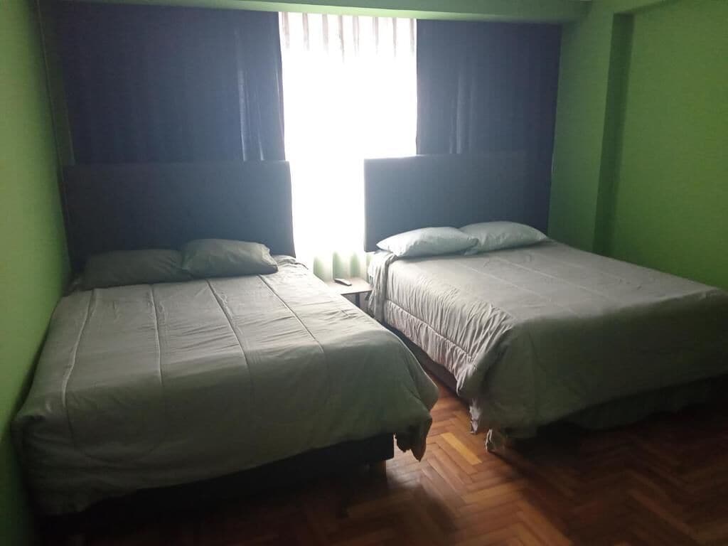 Two single beds with headboards, a nightstand, and a window with curtains.