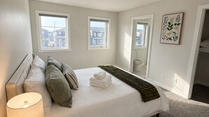 Un dormitorio con cama, lámpara de noche, ventana y puerta.