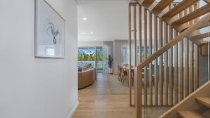 A modern interior with a wooden staircase, a dining area, and a view of the outdoors. - Offshore Escape - Welcome to your dream North Coast escape (Skennars Head)