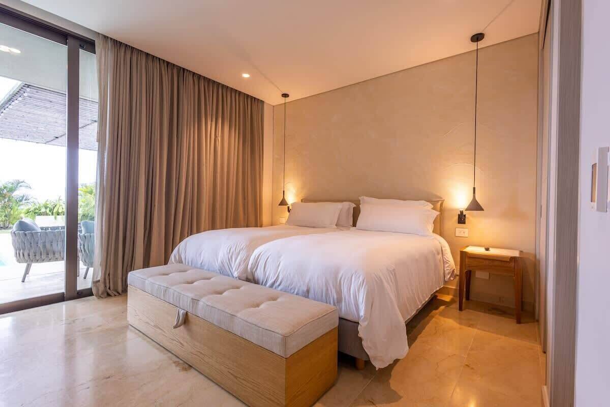 A modern bedroom with a large bed, a bench, and a nightstand.