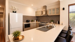 A modern kitchen with a central island, stainless steel appliances, and a view of the outdoors. - Bay Breeze on Thomas (West Busselton)