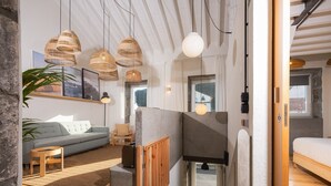 A modern interior with a sofa, wooden flooring, and a staircase leading to an upper level. - ALMA - Island House by GuestReady (Faial da Terra)