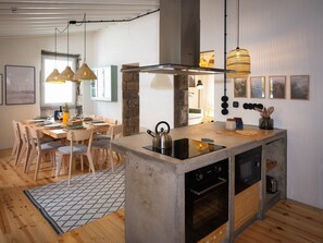 Une cuisine moderne dotée d’un îlot central, d’un coin repas avec des chaises et d’un éclairage suspendu.