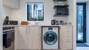 Uma cozinha moderna com máquina de lavar embutida, uma janela e porta que dá para uma varanda.