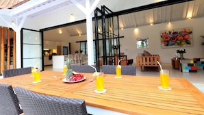 A dining area with a wooden table, wicker chairs, and drinks. - Specious 3Bedroom Rakuen Villa Canggu (Canggu)