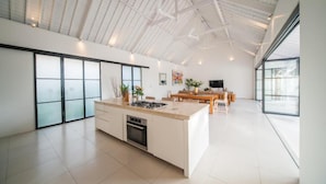 A spacious kitchen with a large island, a dining area, and a high ceiling with exposed beams. - Specious 3Bedroom Rakuen Villa Canggu (Canggu)