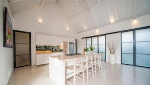A spacious kitchen with a central island, white cabinetry, and a large window. - Specious 3Bedroom Rakuen Villa Canggu (Canggu)