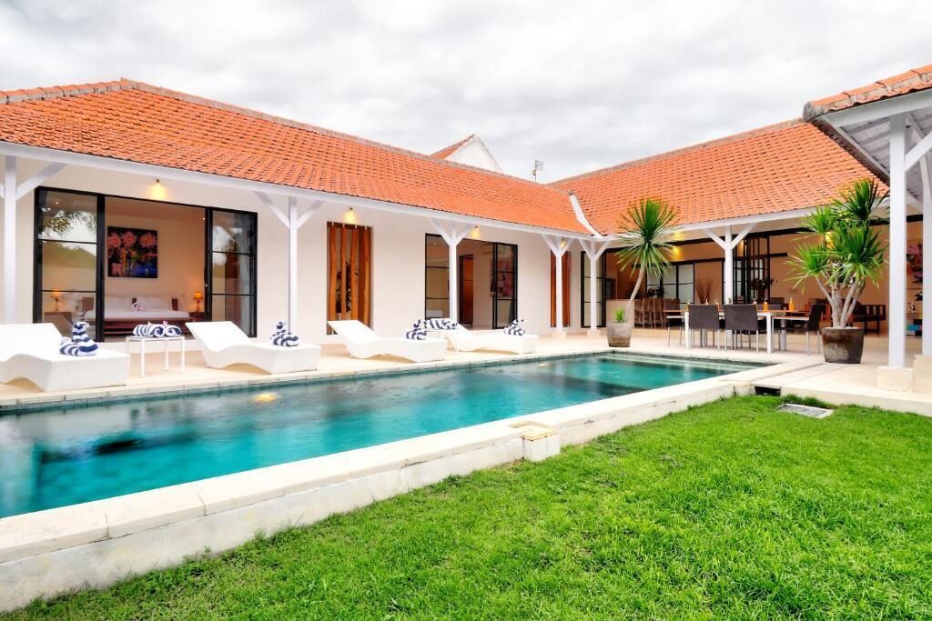 A poolside area with lounge chairs, a covered patio, and a swimming pool.