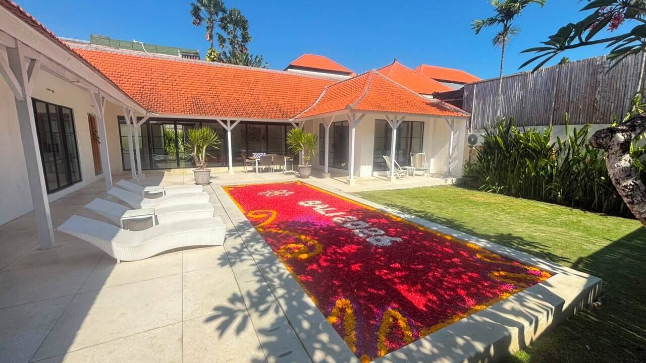 Zona exterior coberta amb un paviment de rajoles, zona d'estar amb caires i un arranjament floral decoratiu.