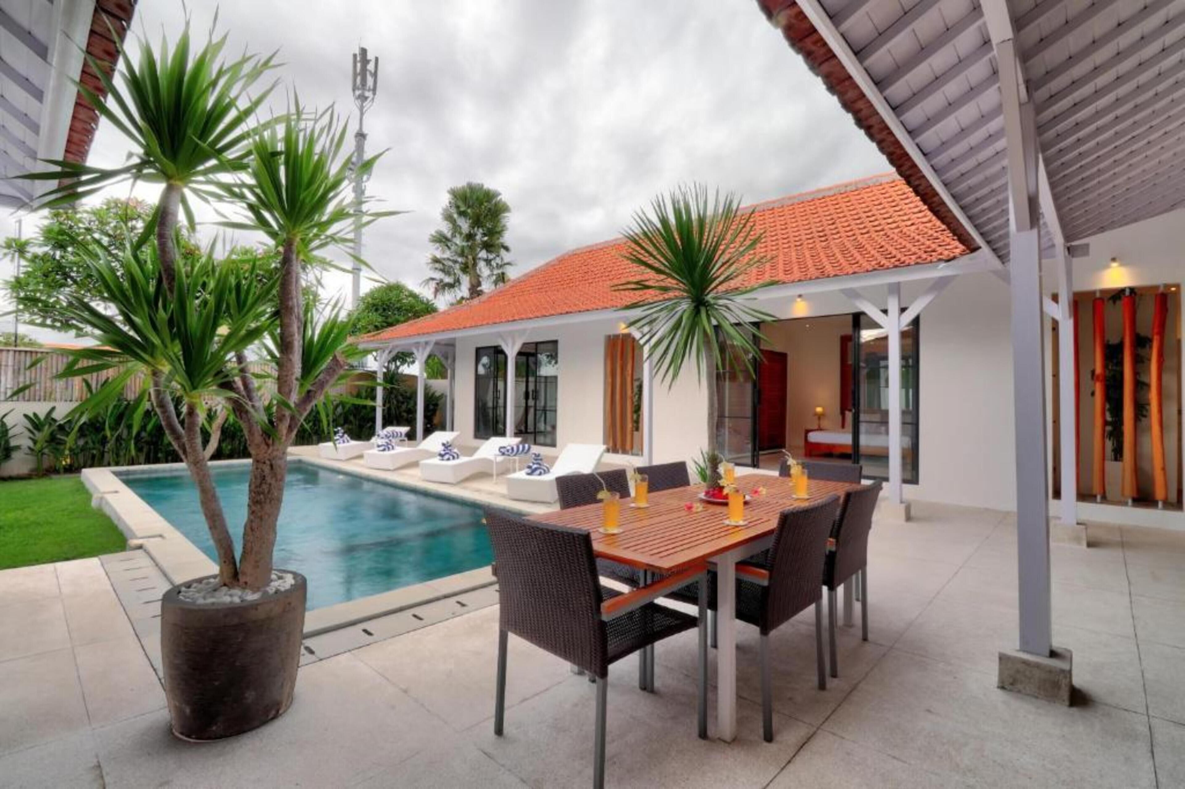 A poolside area with a table and chairs, a covered patio, and a swimming pool.